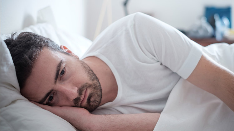 Depressed man lying in his bed and feeling bad