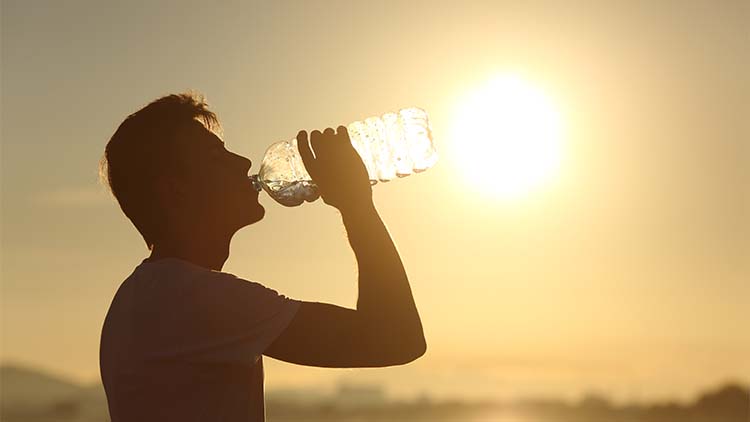 Fitness man silhouette drinking water from a bottle