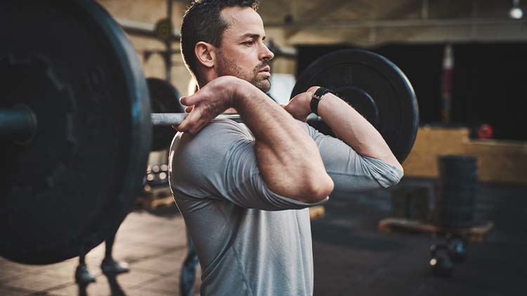 Man pulling up large barbell in fitness class