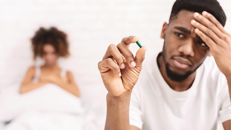 Upset black guy taking potency pill before sex with girlfriend