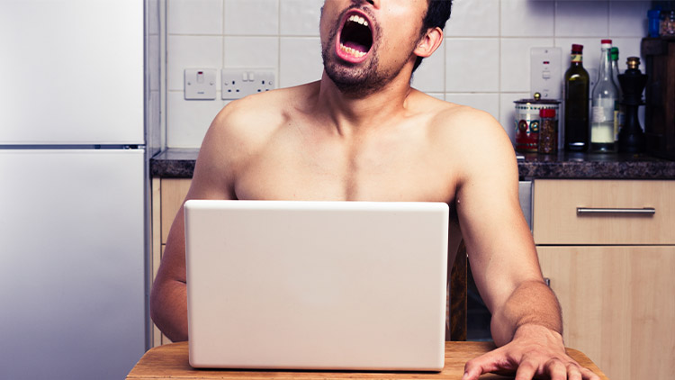 Young naked man watching pornography in his kitchen