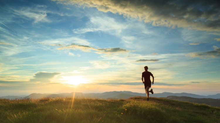 Athlete running through mountains during sunset