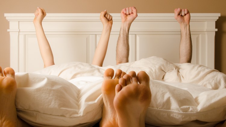 Couple celebrating in bed under sheets