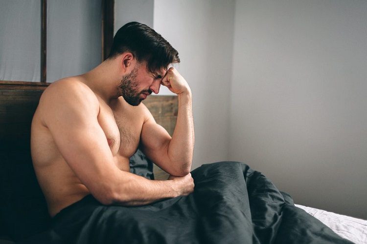 Frustrated man sitting in bed