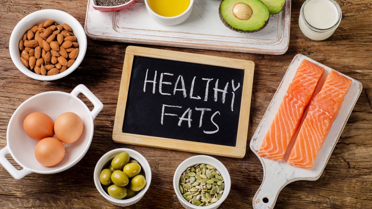 Healthy fats on chalkboard surrounded by suitable foods