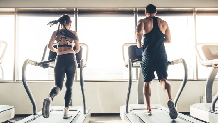 Man and woman running on treadmill in the gym