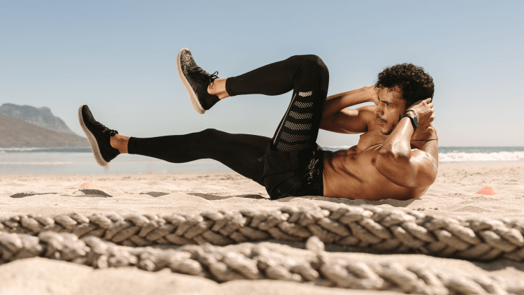 Man doing abdomen workout on beach