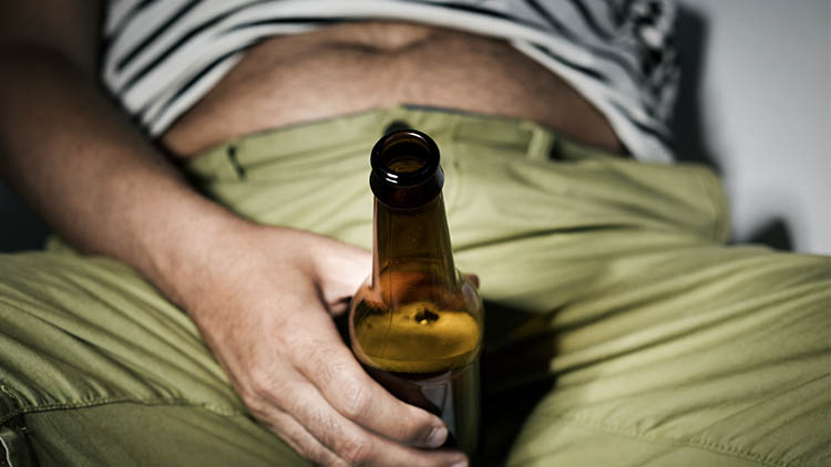 man drinking a beer sitting in the sofa