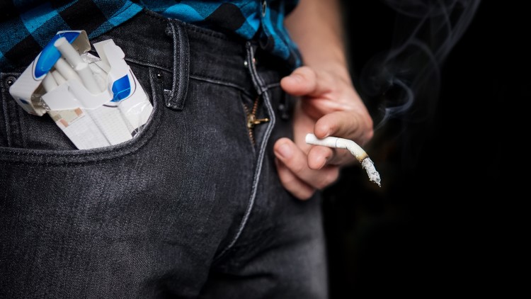 Man holding floppy cigarette in front of groin