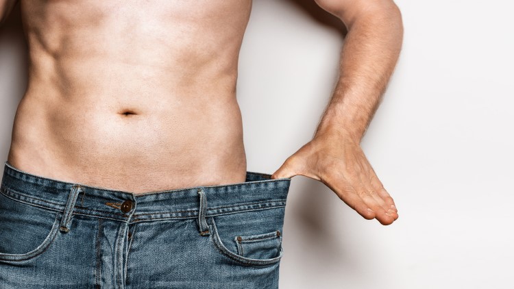 Man pulling waistband of jeans to highlight weight loss