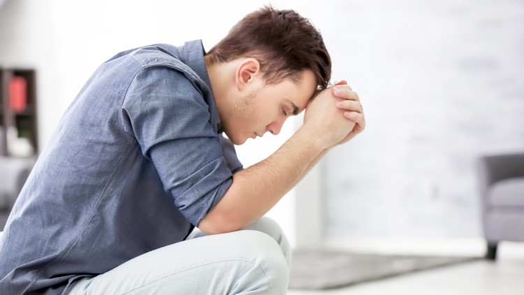 Depressed man sat at home looking at the floor