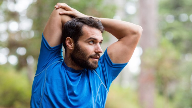 Man stretching arms in forest