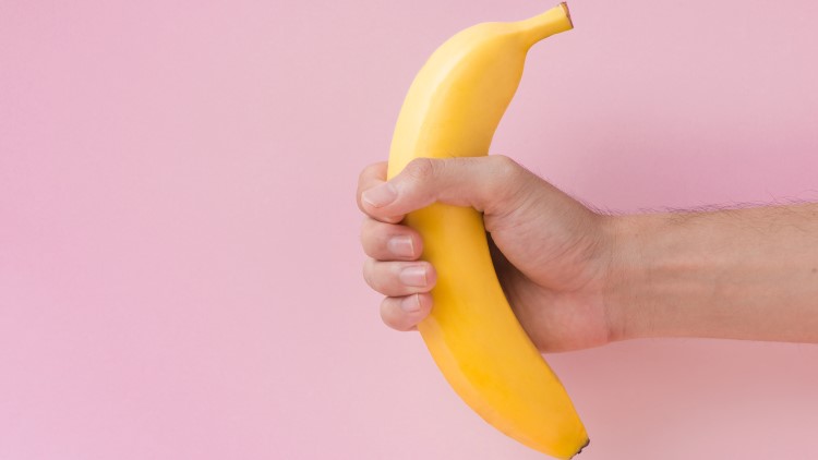 Man holding banana on pink background