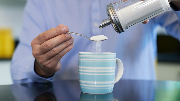 Mature man adding sugar to hot drink