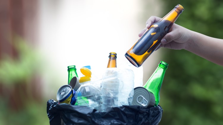 Person putting empty bottle into recycle can