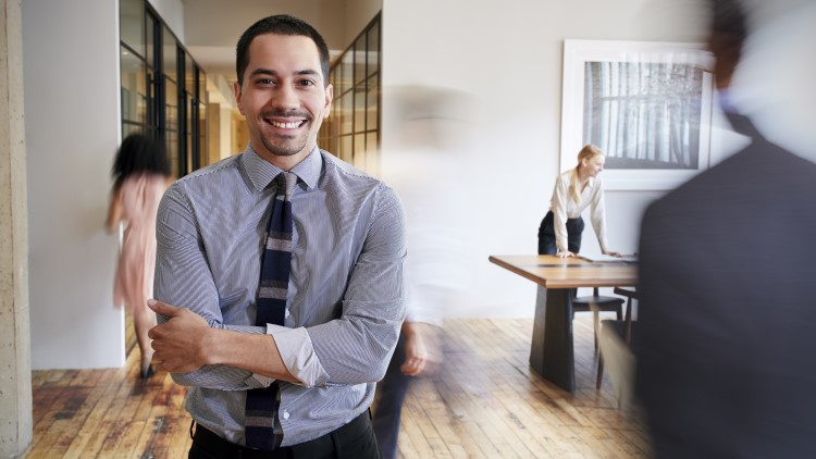 Young Hispanic man in busy office