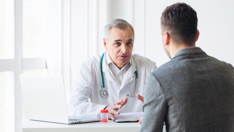 Senior doctor consulting with young male patient