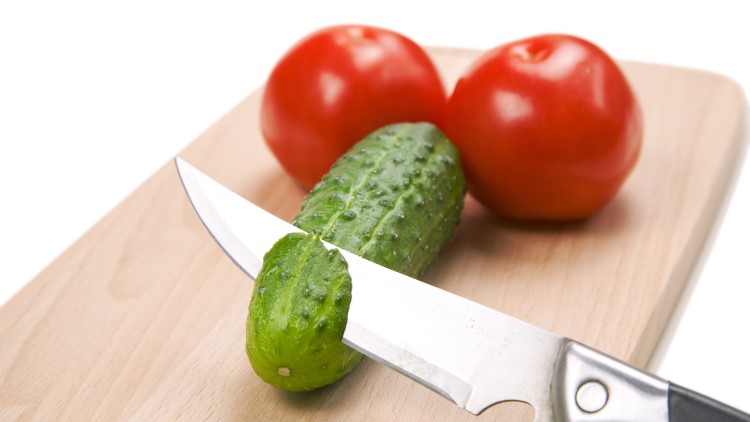 Two tomatoes and one chopped cucumber on cutting board