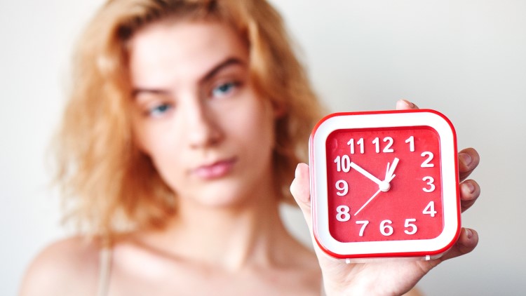 Annoyed lady holding clock close up