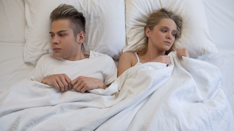 Young couple looking away from each other in bed