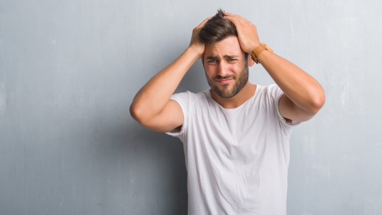 Young man holding top of head looking stressed out