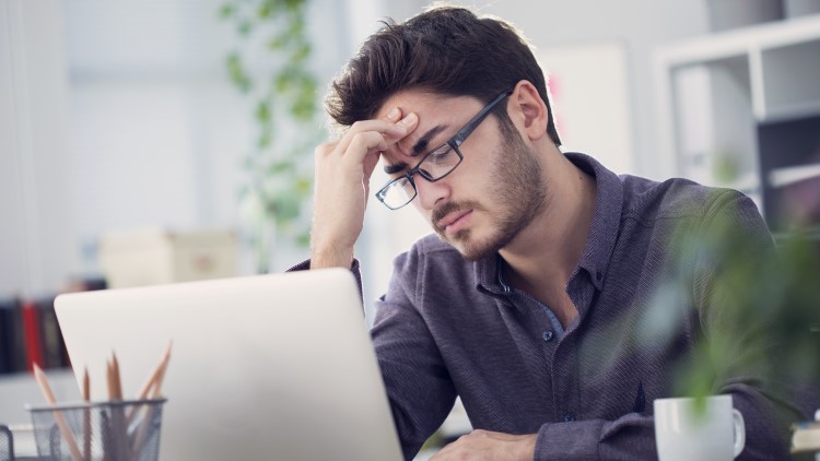 Young man working on laptop with headache